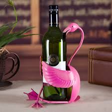 Pink metal Flamingo Wine Holder holding a green wine bottle on a table with blurred background.