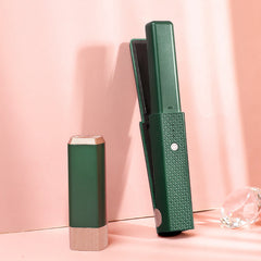 Hair Wand Pro in dark green with textured grip standing next to matching protective cap on pink background