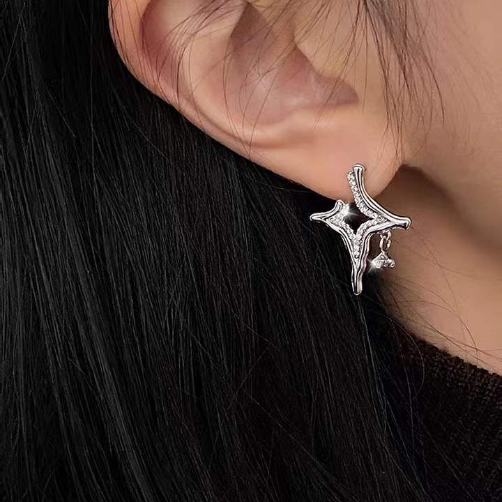 Close-up of a silver Asterism Rhinestone Earrings worn on the ear with dark hair background.