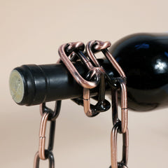 Close-up of a dark wine bottle suspended by linked metal chains in the Magic Iron Chain Wine Bottle Holder