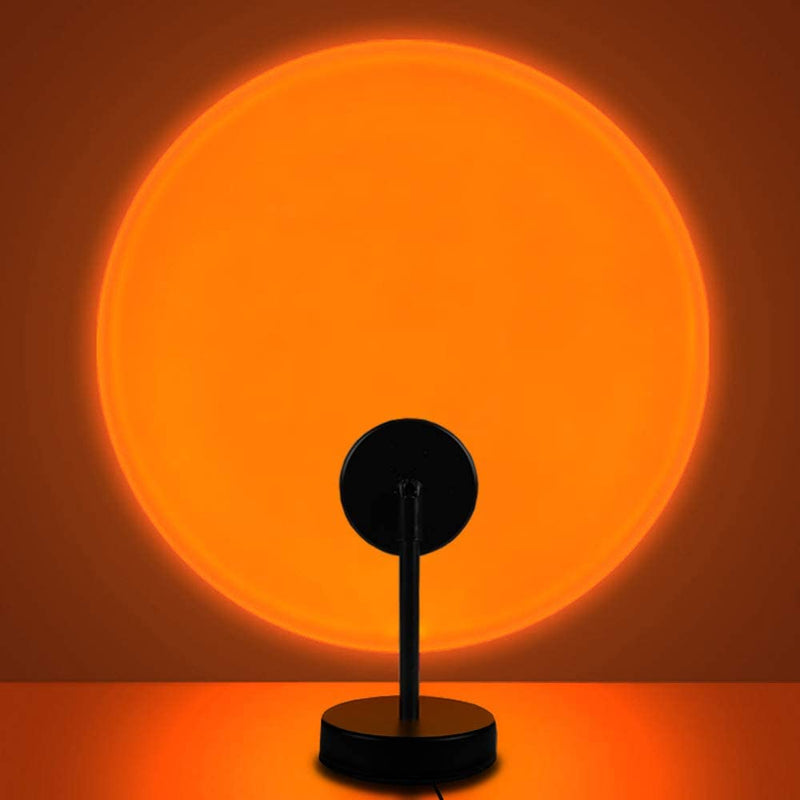 Modern desk lamp casting a large circular orange glow on the wall, named Sunset Lamp.