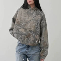 Model wearing a loose fit Camouflage Streetwear Hoodie with a tree branch pattern and blue denim jeans.