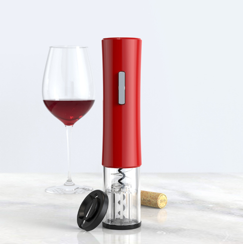 Red automatic wine bottle opener with corkscrew and a glass of red wine on a white surface.