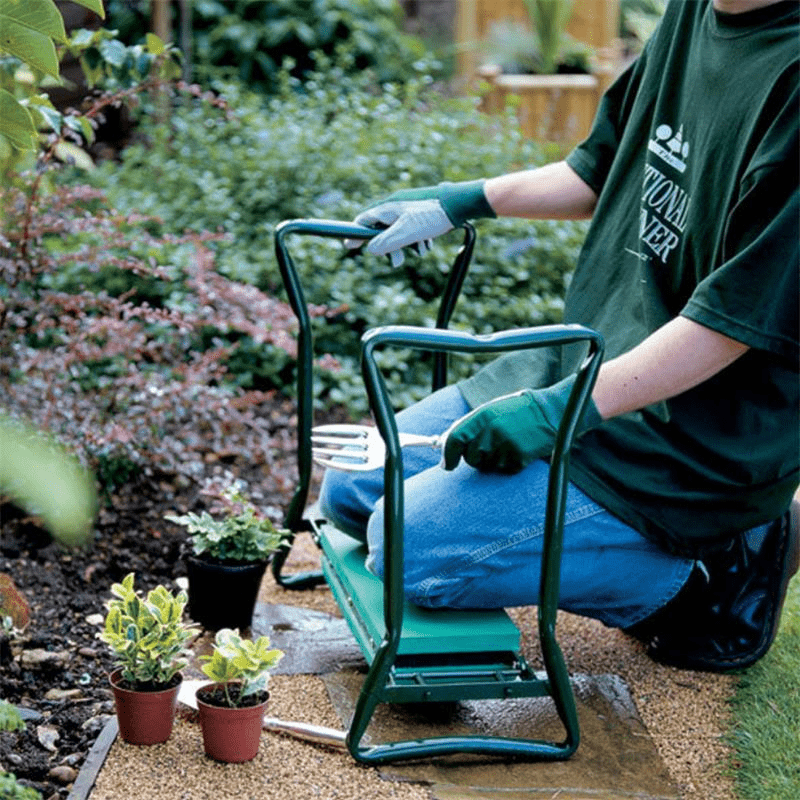 Person using a green Garden Kneeler with gloves to tend plants in a garden bed beside small potted plants