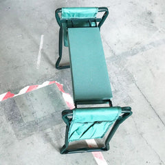 Green padded Garden Kneeler with pockets on a concrete floor, designed for comfortable gardening tasks.