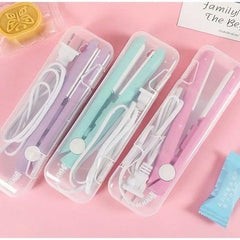 Three Ceramic Mini Hair Straighteners in pastel purple, mint green, and pink with cords in transparent cases on a pink surface.