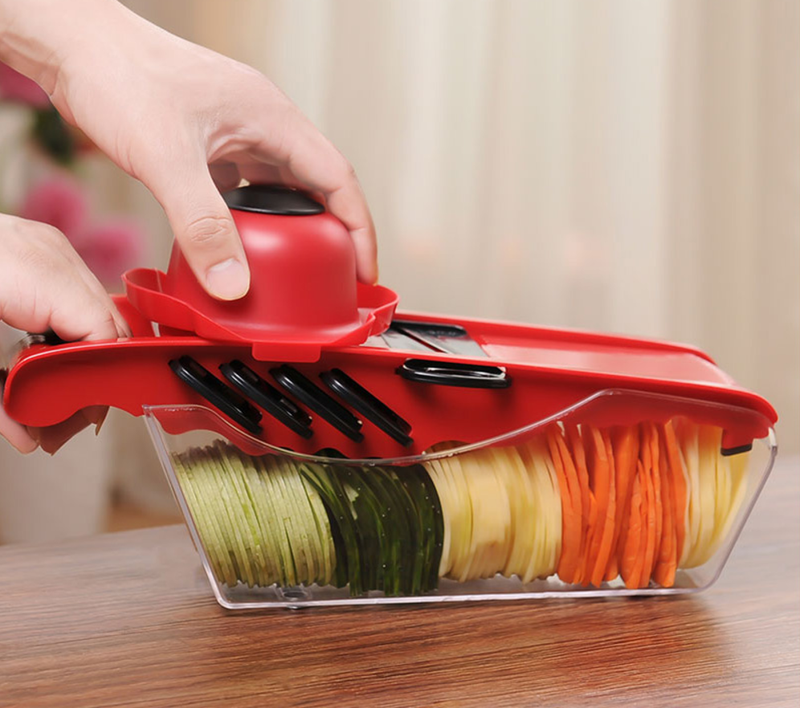 Multifunction 6 Blades Kitchen Slicer slicing vegetables with protective hand guard and container below.
