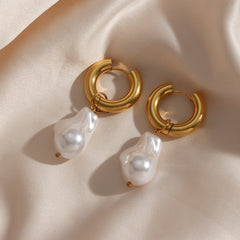 Gold hoop earrings with irregular white pearls designed as Water Drop Earrings on a soft beige fabric background.