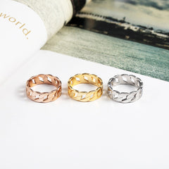 Three Cassie Ring versions in rose gold, yellow gold, and silver with a woven design on a white surface.
