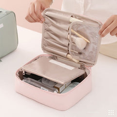 Pink makeup bag open showing organized compartments with beauty products and brushes inside