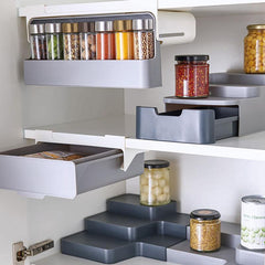 Kitchen Self-Adhesive Wall-Mounted Spice Organizer holding spice jars inside a kitchen cabinet with sliding drawers and tiered shelves.