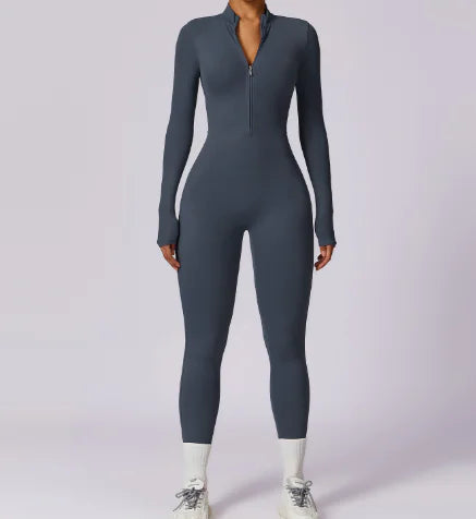 Woman wearing a dark gray Women's Warm Zipper Yoga Jumpsuit with long sleeves and a front zipper, paired with white sneakers.