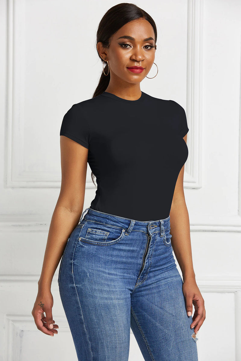 Woman wearing a black Women's Solid Color Base Shirt paired with high-waisted blue jeans against white wall background