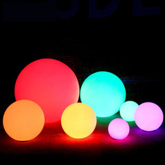 Group of colorful Waterproof Garden Ball LED Lights for Outdoor glowing in red, blue, yellow, orange, and purple hues at night