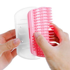 Hands holding pink and white Cat Self Groomer Corner Brush showing bristle attachment and base plate.
