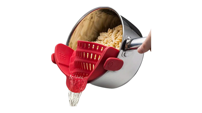 Red Silicone Pot Strainer clipping pasta in a silver pot while draining water from it.
