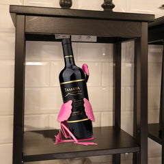 Flamingo Wine Holder holding a wine bottle with pink flamingo design on a dark wooden shelf.