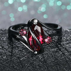 Crystal Ring featuring a marquise red gemstone with two smaller pink stones set in black metal band.