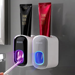 Wall Mount Automatic Toothpaste Dispenser in black and white with glowing toothpaste outlet dispensing on toothbrush