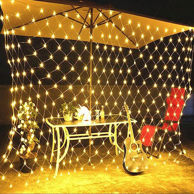 Net Mesh Solar Fairy Lights glowing warmly in a net pattern around an outdoor table with guitar and plants.